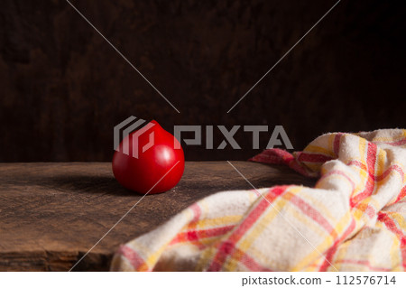 Pink tomato and red towel on wooden background.. Pink tomato and red towel on wooden background.. 112576714