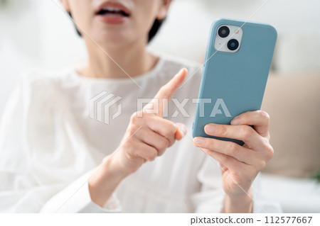 Angry woman holding a smartphone 112577667
