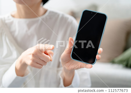 Angry woman holding a smartphone 112577673