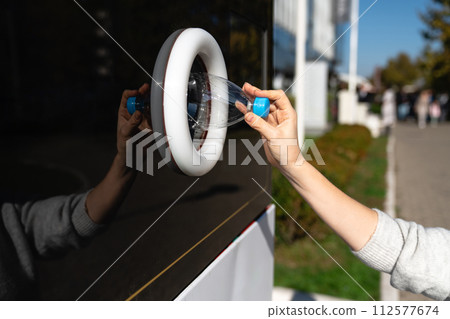 Woman uses a self service machine to receive used plastic bottles and cans on a city street.. 112577674