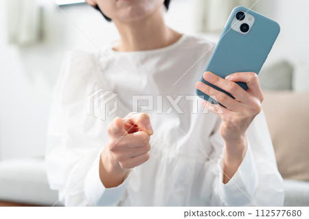 Angry woman holding a smartphone Angry woman holding a smartphone 112577680