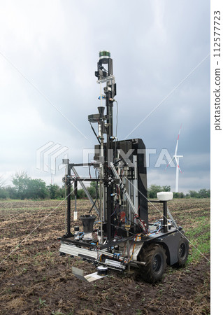 Autonomous robot for measuring soil quality in an agricultural field. Wind turbine on a horizon. Smart farming concept 112577723