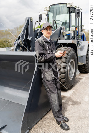 Serviceman with digital tablet on a background of the tractor 112577935