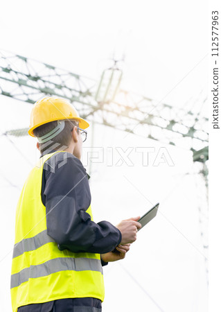 Engineer with digital tablet on a background of power line tower Engineer with digital tablet on a background of power line tower 112577963