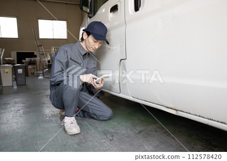 一名工人正在估算修理受損汽車的費用 一名工人正在估算修理受損汽車的費用 112578420