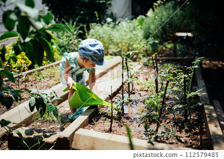 Adorable girl watering garden plants with watering can 112579485