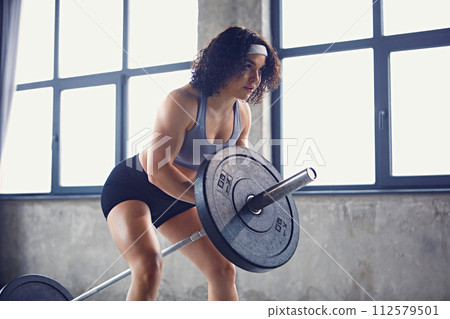 Dynamic portrait of young athletic woman doing total-Body exercises for chest with only barbell in motion at gym. Dynamic portrait of young athletic woman doing total-Body exercises for chest with only barbell in motion at gym. 112579501