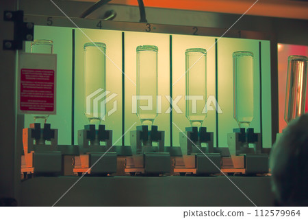 A distillery and winery pours the drink into glass bottles on conveyor lines. Industrial works, automated food and beverage production. A distillery and winery pours the drink into glass bottles on conveyor lines. Industrial works, automated food and beverage production. 112579964