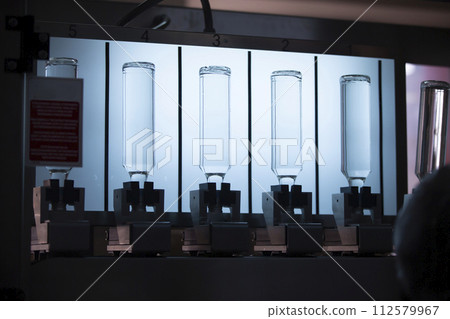 A distillery and winery pours the drink into glass bottles on conveyor lines. Industrial works, automated food and beverage production. A distillery and winery pours the drink into glass bottles on conveyor lines. Industrial works, automated food and beverage production. 112579967