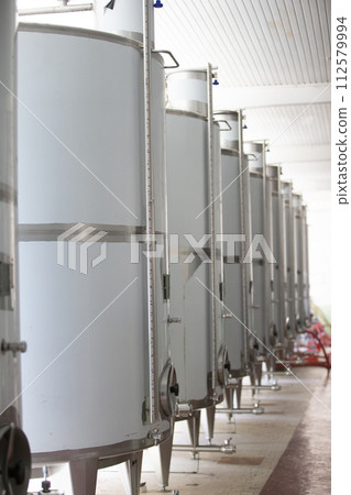 Industrial metal tanks for wine at a plant for the production of alcoholic beverages. Industrial metal tanks for wine at a plant for the production of alcoholic beverages. 112579994