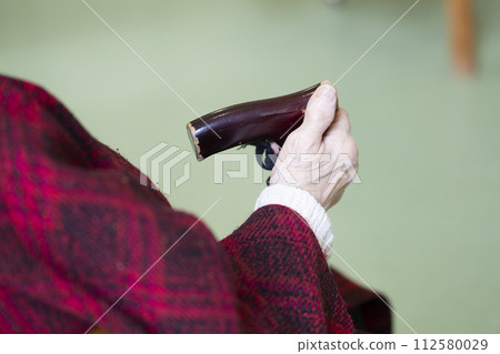 The old man's hands are holding a stick. Old age and age concept. The old man's hands are holding a stick. Old age and age concept. 112580029