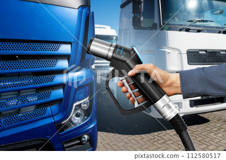 Hand with H2 fueling nozzle on a background of hydrogen fuel cell truck. Eco-friendly commercial vehicle concept.. Hand with H2 fueling nozzle on a background of hydrogen fuel cell truck. Eco-friendly commercial vehicle concept.. 112580517