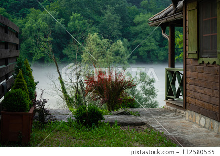 Porch of a wooden house in the forest on the river bank Porch of a wooden house in the forest on the river bank 112580535