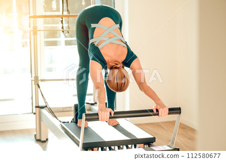 Woman has anaerobic workout session using Pilates machine in the gym Woman has anaerobic workout session using Pilates machine in the gym 112580677