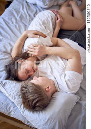 a young couple is lying on the bed, the girl is on the boy's shoulder, tender hugs a young couple is lying on the bed, the girl is on the boy's shoulder, tender hugs 112580840