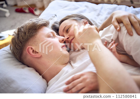 a young couple is lying on the bed, the girl is on the boy's shoulder, tender hugs a young couple is lying on the bed, the girl is on the boy's shoulder, tender hugs 112580841