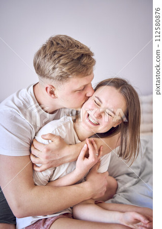 a man hugs his wife from behind, face to face 112580876