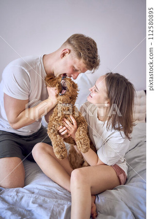 a couple plays with a cockapoo girl on a bed, minimalism a couple plays with a cockapoo girl on a bed, minimalism 112580895