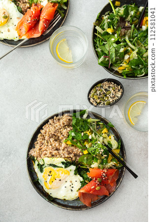 Buckwheat with fried egg and salmon fish, mix salad with fresh herbs and peppers 112581041