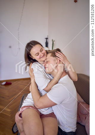 a young couple in home clothes gently hug in the living room, minimalism 112581206