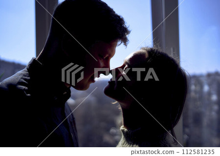 beautiful young couple kissing in the backlight against the window 112581235