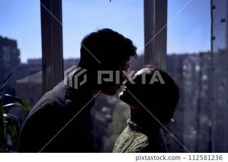 beautiful young couple kissing in the backlight against the window 112581236