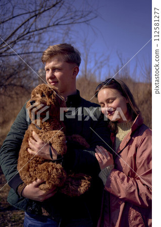 wife, husband and their cockapoo cuddle in the spring sun 112581277
