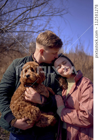 wife, husband and their cockapoo cuddle in the spring sun wife, husband and their cockapoo cuddle in the spring sun 112581278