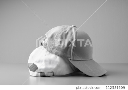 Two White Baseball Caps on a White Background 112581609