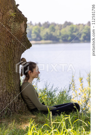 Contemplative Woman Enjoying Solitude by the Lake Shore 112581786