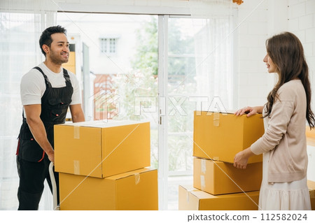 Homeowners receive professional moving aid indoors. Uniformed movers unload boxes from truck ensuring customer satisfaction during relocation. Efficient service and teamwork shown. Moving Day 112582024
