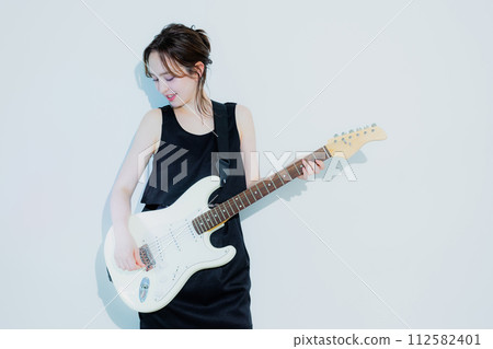 A woman playing an electric guitar 112582401