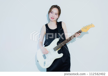 A woman playing an electric guitar 112582402
