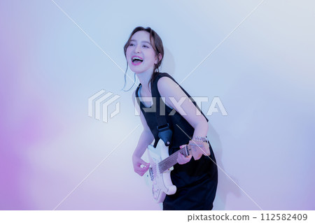 A woman playing an electric guitar 112582409