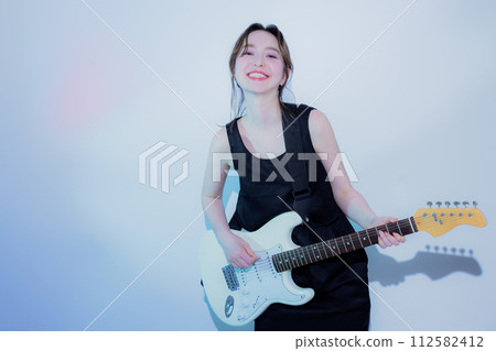 A woman playing an electric guitar 112582412