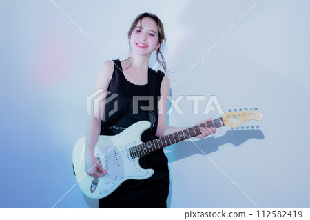 A woman playing an electric guitar 112582419