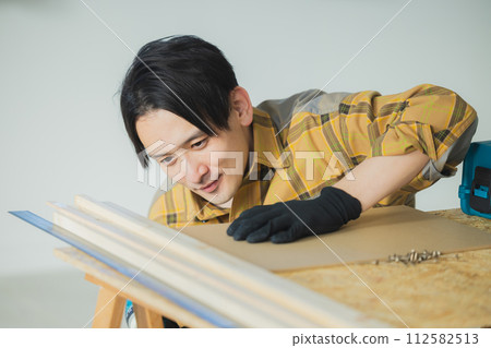 A young man working with an electric screwdriver A young man working with an electric screwdriver 112582513