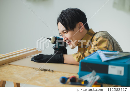 A young man working with an electric screwdriver A young man working with an electric screwdriver 112582517