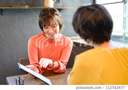 Two women choosing menus at a cafe Two women choosing menus at a cafe 112582677