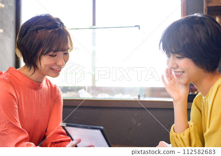 Two women choosing menus at a cafe Two women choosing menus at a cafe 112582683