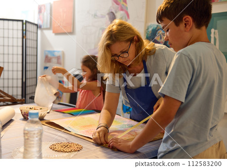 Caucasian middle aged woman educator works with children, teaching art in the development center. People. Visual art. 112583200