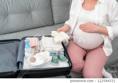 Picture of how a woman in late pregnancy packs things for the maternity hospital Picture of how a woman in late pregnancy packs things for the maternity hospital 112584251