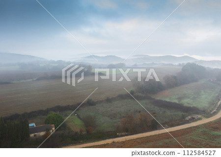 Aerial view of cultivated plots and hedges in autumn with fog. Aerial view of cultivated plots and hedges in autumn with fog. 112584527