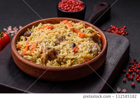 Delicious pilaf with vegetables, salt, spices and herbs in a ceramic plate 112585182