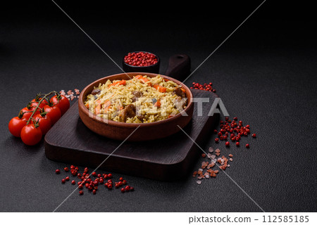 Delicious pilaf with vegetables, salt, spices and herbs in a ceramic plate 112585185