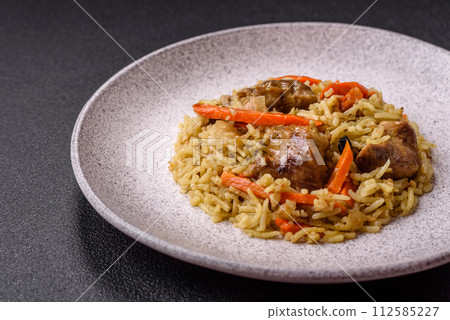 Delicious pilaf with vegetables, salt, spices and herbs in a ceramic plate 112585227
