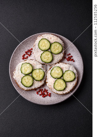 Delicious vegetarian sandwich with grilled toast, cream cheese, cucumbers and seeds 112585256