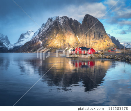 Red rorbuer and snowy rocks lighted by sun, blue sea at sunset 112585578