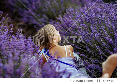 A middle-aged woman lies in a lavender field and enjoys aromatherapy. Aromatherapy concept, lavender oil, photo session in lavender A middle-aged woman lies in a lavender field and enjoys aromatherapy. Aromatherapy concept, lavender oil, photo session in lavender 112585640