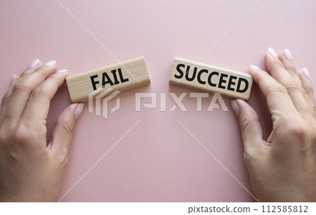 Fail or Succeed symbol. Concept word Fail or Succeed on wooden blocks. Businessman hand. Beautiful pink background. Business and Fail or Succeed concept. Copy space Fail or Succeed symbol. Concept word Fail or Succeed on wooden blocks. Businessman hand. Beautiful pink background. Business and Fail or Succeed concept. Copy space 112585812